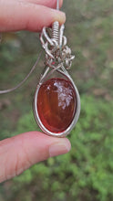 Load and play video in Gallery viewer, Rare Ruby-Red Coloured Amber Pendant set in Sterling Silver
